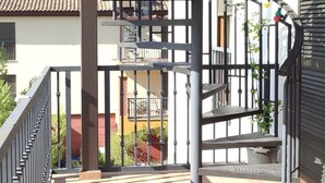 Un escalier en colimaçon avec une rampe en métal, donnant sur un bâtiment doté de balcons en arrière-plan.
