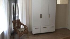 Une pièce avec une armoire blanche, une chaise en osier et un luminaire suspendu.