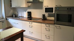 Une cuisine moderne avec des meubles blancs, une hotte en acier inoxydable, un four à micro-ondes et un four traditionnel.