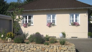 Un bâtiment à deux étages, doté d’un toit recouvert de tuiles brunes, de fenêtres à cadre blanc et de fondations en pierre.