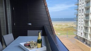 Ein Balkon mit Tisch für zwei Personen, ausgestattet mit einer Champagnerflasche und Gläsern.