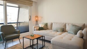 Ein Wohnzimmer mit einer Couch, einem Sessel und einem kleinen Tisch mit einer Lampe.