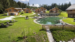 A resort with wooden cabins, a swimming pool, and sun loungers. - Cosy Chalet in Wolting With Natural Swimming Pond (Tamsweg)