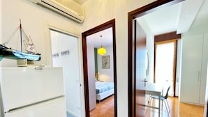 A compact living space with a kitchenette, a bed, a dining area, and a bathroom. - Apartment Near Porto Santa Margherita Beach (Caorle)