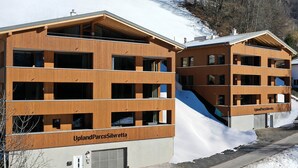 Ein modernes Gebäude mit mehreren Balkonen und einer Skipiste.