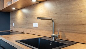 Eine moderne Küche mit Spüle aus Edelstahl, einer Holz Arbeitsplatte und eingebauten Schränken.