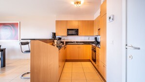 A modern kitchen with wooden cabinets, a microwave, a coffee maker, and a sink. - Apartment in Koksijde Near the Sea (Koksijde)