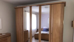 Um quarto com um guarda-roupa de madeira, uma cama com almofadas e uma cômoda.