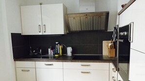 A kitchen with white cabinets, a black countertop, and a wooden floor. - Gezellig Huisje (Zeltingen-Rachtig)