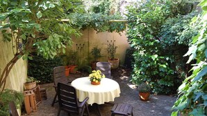 A patio with a round table, four chairs, and potted plants. - Gezellig Huisje (Zeltingen-Rachtig)