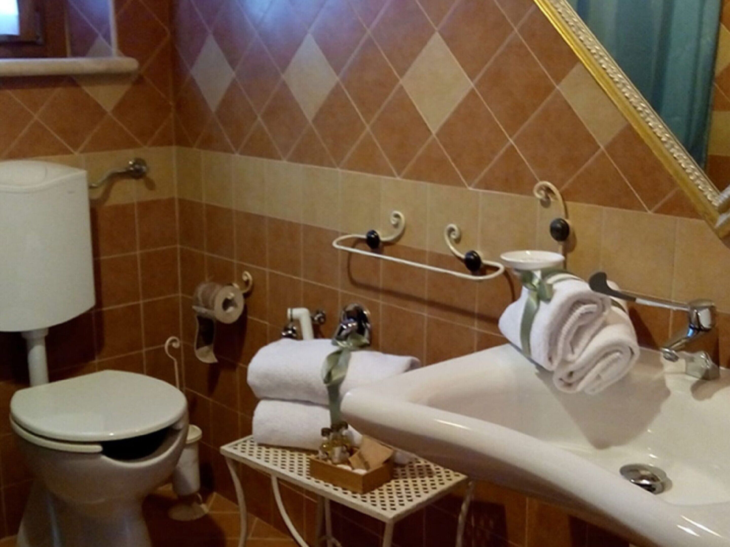 Un baño con inodoro, lavabo y perchero para toallas.