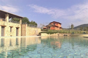Ein Schwimmbecken mit Steingebäuden im Hintergrund.