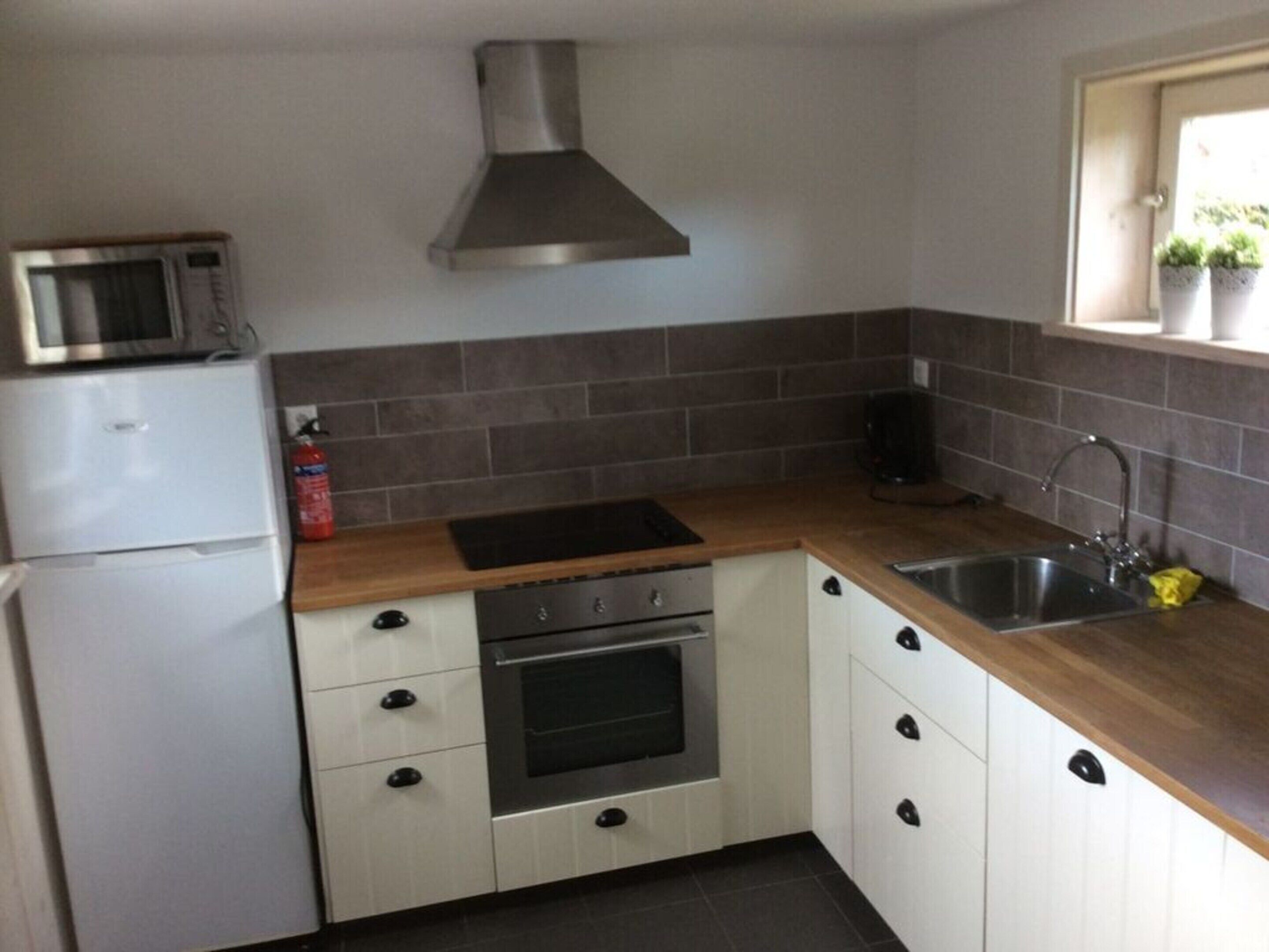 A compact kitchen with a microwave, oven, and sink.