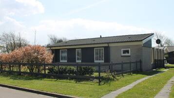A single-story house with a dark exterior, a sloped roof, and a satellite dish on the roof.
