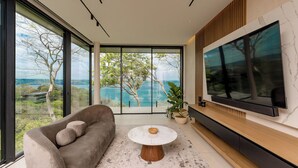 Ein modernes Wohnzimmer mit großem Fernseher, bequemen Sitzmöglichkeiten und Seeblick.