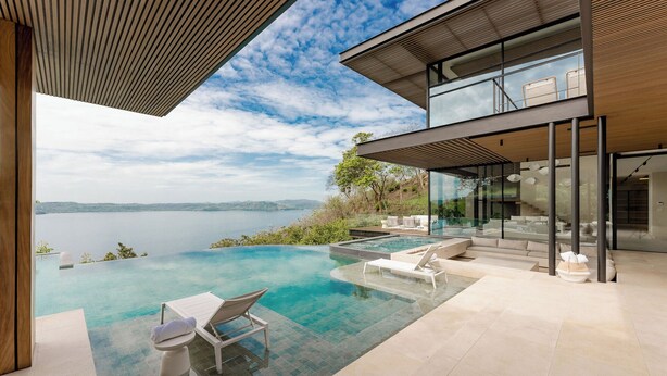 Ein modernes Haus mit einem Glas-Endlospool mit Blick auf einen See.