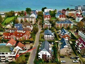 An aerial view of a residential area with houses, a main road, and a body of water in the background. - Herring Gull (Scharbeutz)