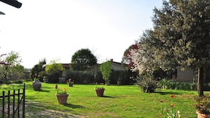 A well-maintained garden with potted plants, a stone pathway, and a wooden fence. - Farmhouse With Spacious Garden and Pool (Asciano)