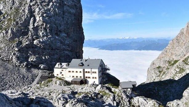 A mountain lodge with a large rock formation nearby, offering a view of distant mountains. - Holiday Apartment in Bavaria (Schoenau am Koenigssee)