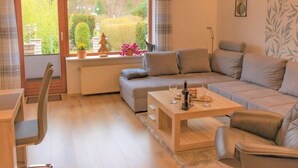 A modern living room with a sofa, a coffee table, and a dining area. - Holiday Home Mountain View (Langelsheim)