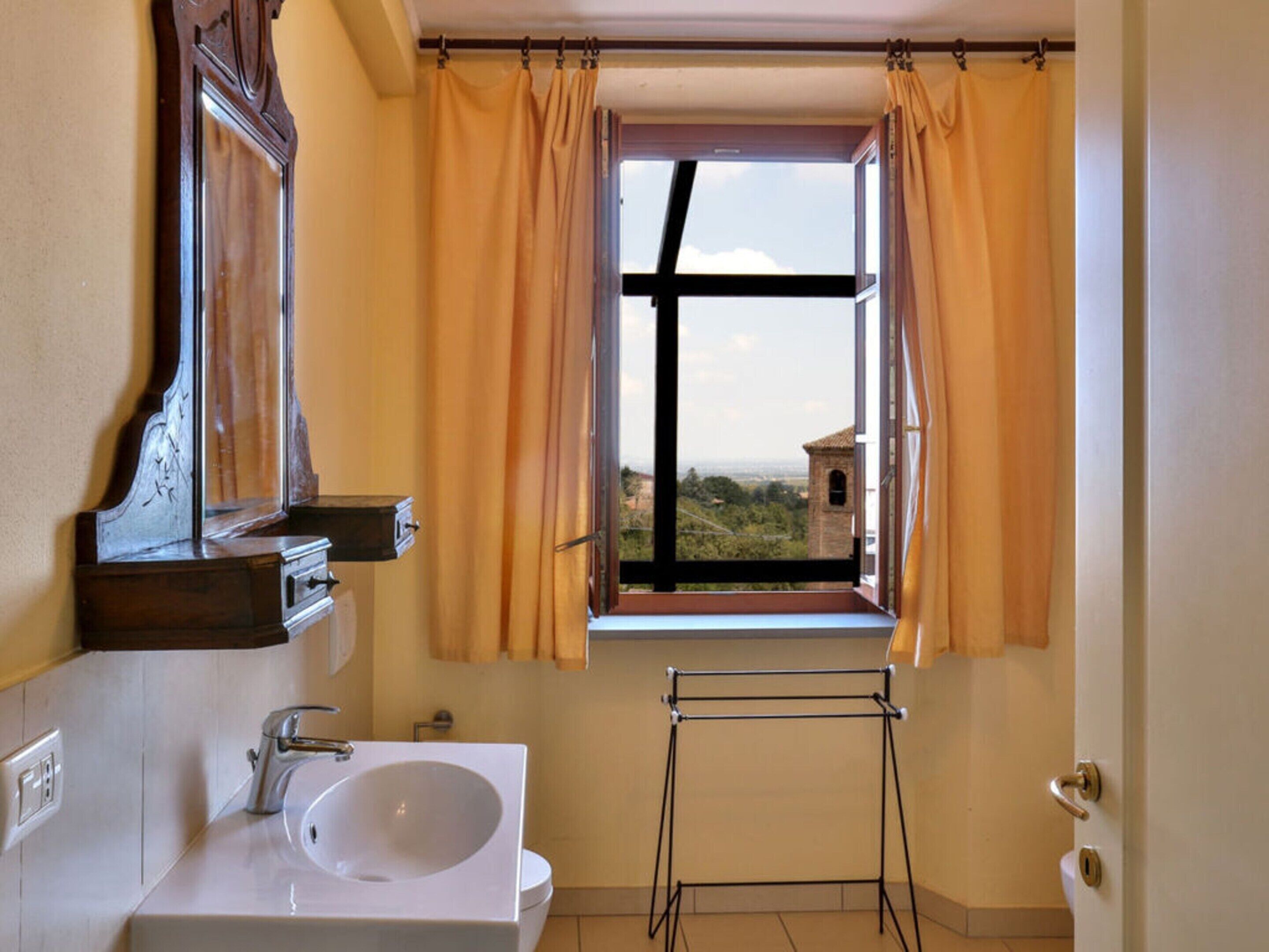 Un baño con un ventanal grande, un lavabo y un perchero para toallas.
