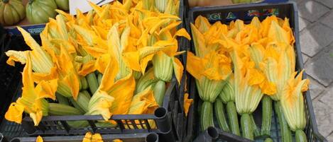 A market stall with yellow flowers and green vegetables.