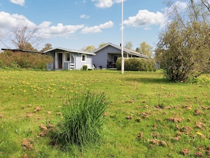 Ein zweistöckiges Haus mit Veranda und Rasen vor der Fassade.
