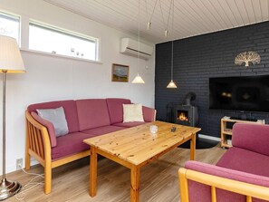 A cozy living room with a sofa, a wooden table, a TV, and a fireplace. - 7 Person Holiday Home in Hals (Hals)