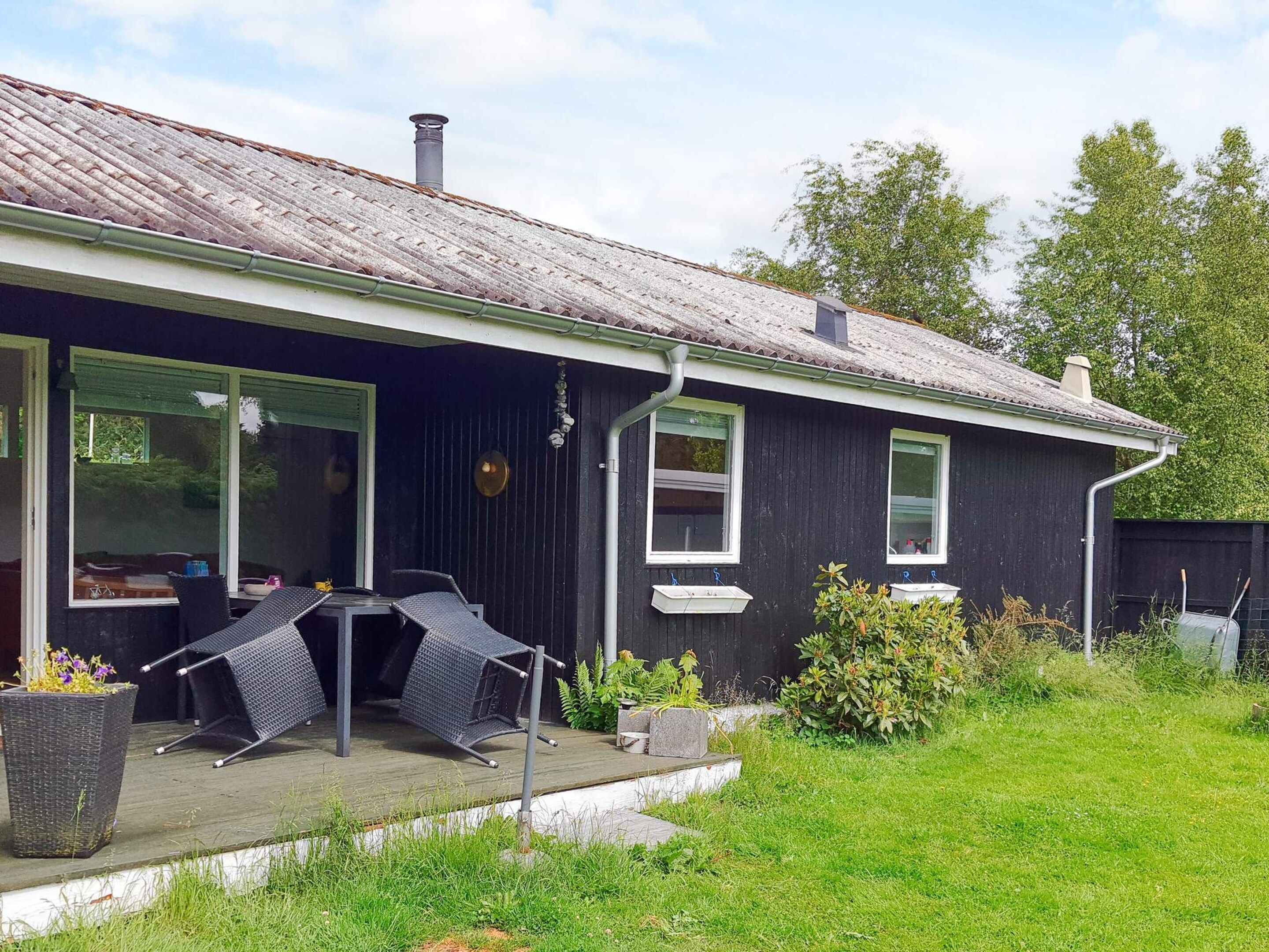 A house with a covered patio, a dining table with chairs, and a small garden area.