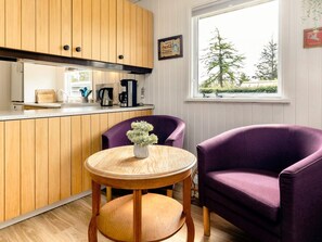 A compact kitchen with wooden cabinets, a coffee maker, and a window with a view of trees. - 7 Person Holiday Home in Hals (Hals)