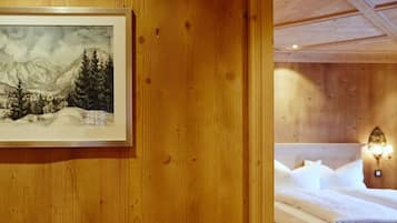 A wooden wall with a framed painting of a mountainous landscape.