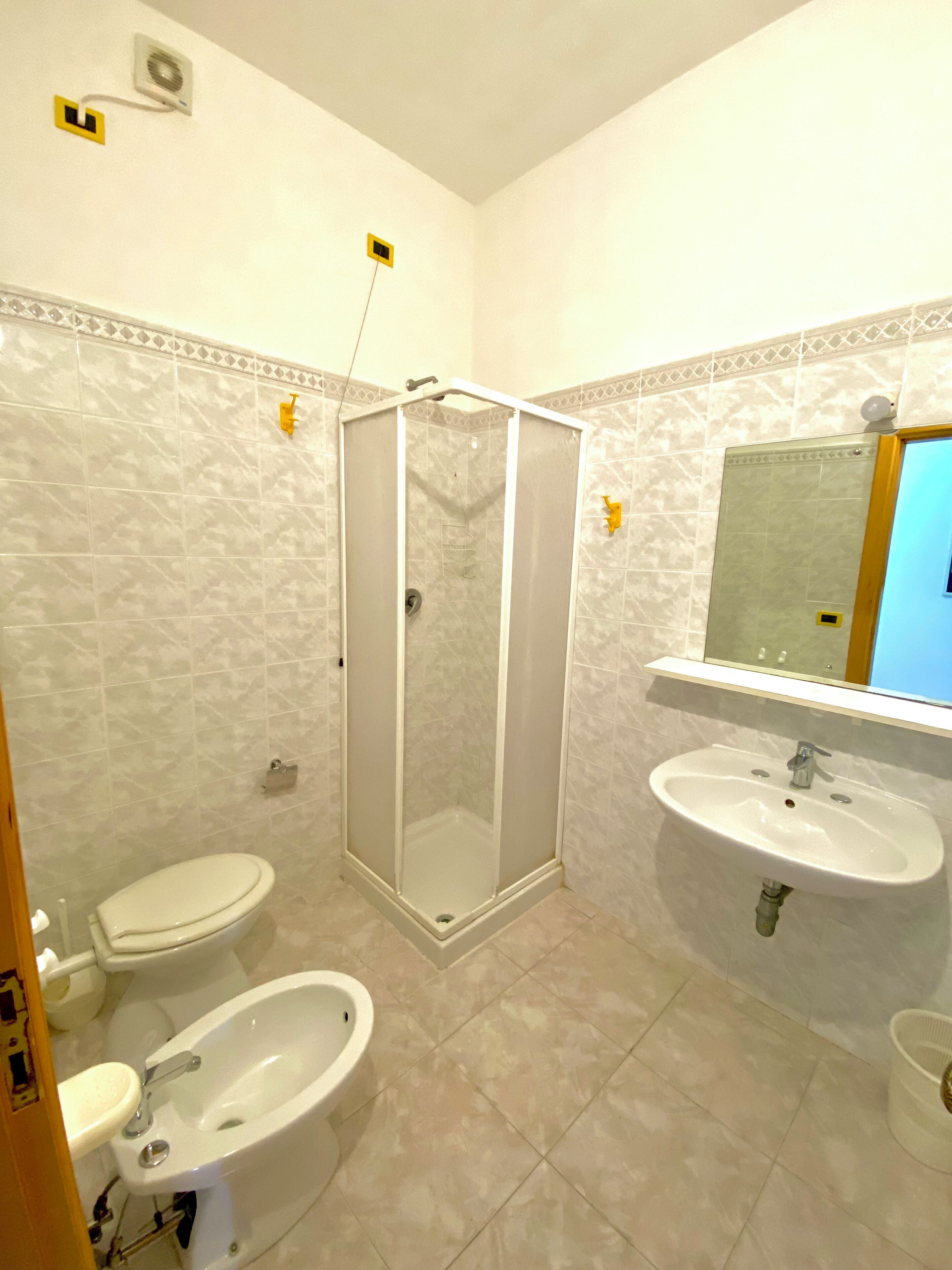 Une salle de bain avec une douche à parois de verre, deux lavabos et des toilettes.