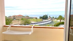 A balcony with a view of a coastal area, including houses and a road. - Residence Felix (Ricadi)