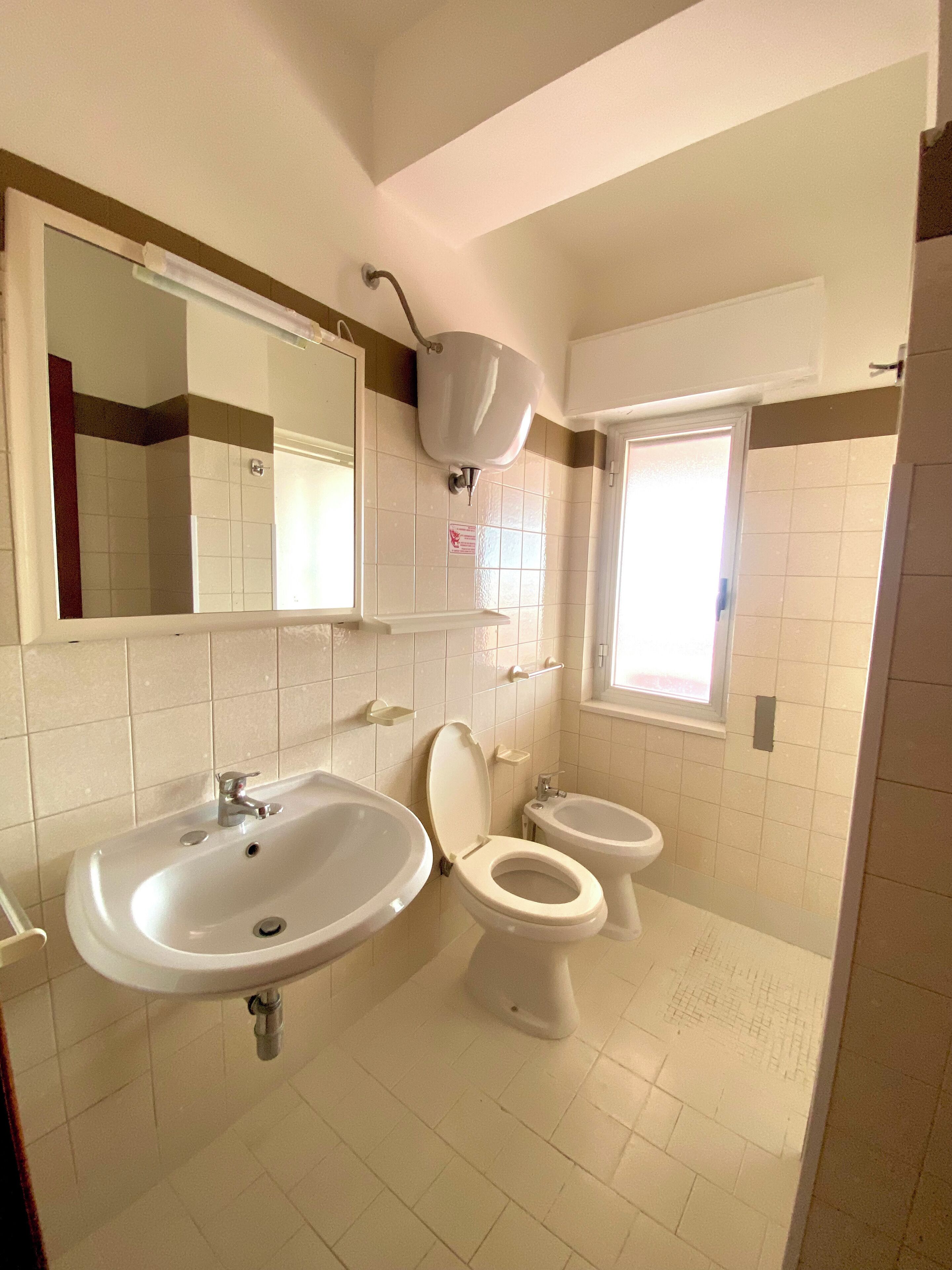 A bathroom with a sink, toilet, and bidet.