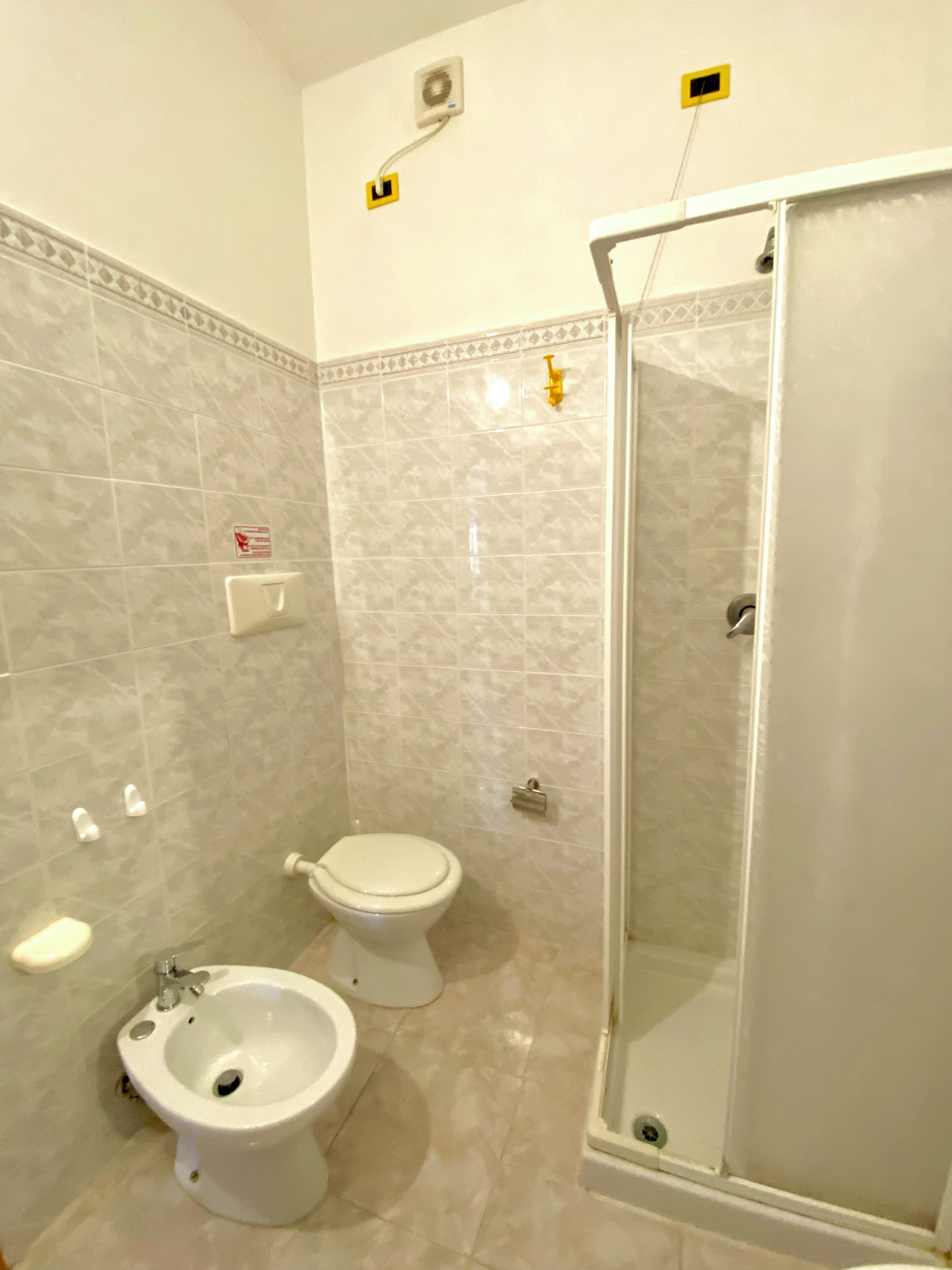 Ein Badezimmer mit Toilette, Bidet und einer Duschkabine.