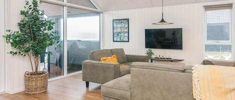 Una sala moderna con un sofá modular, un televisor de pantalla plana y un ventanal grande.
