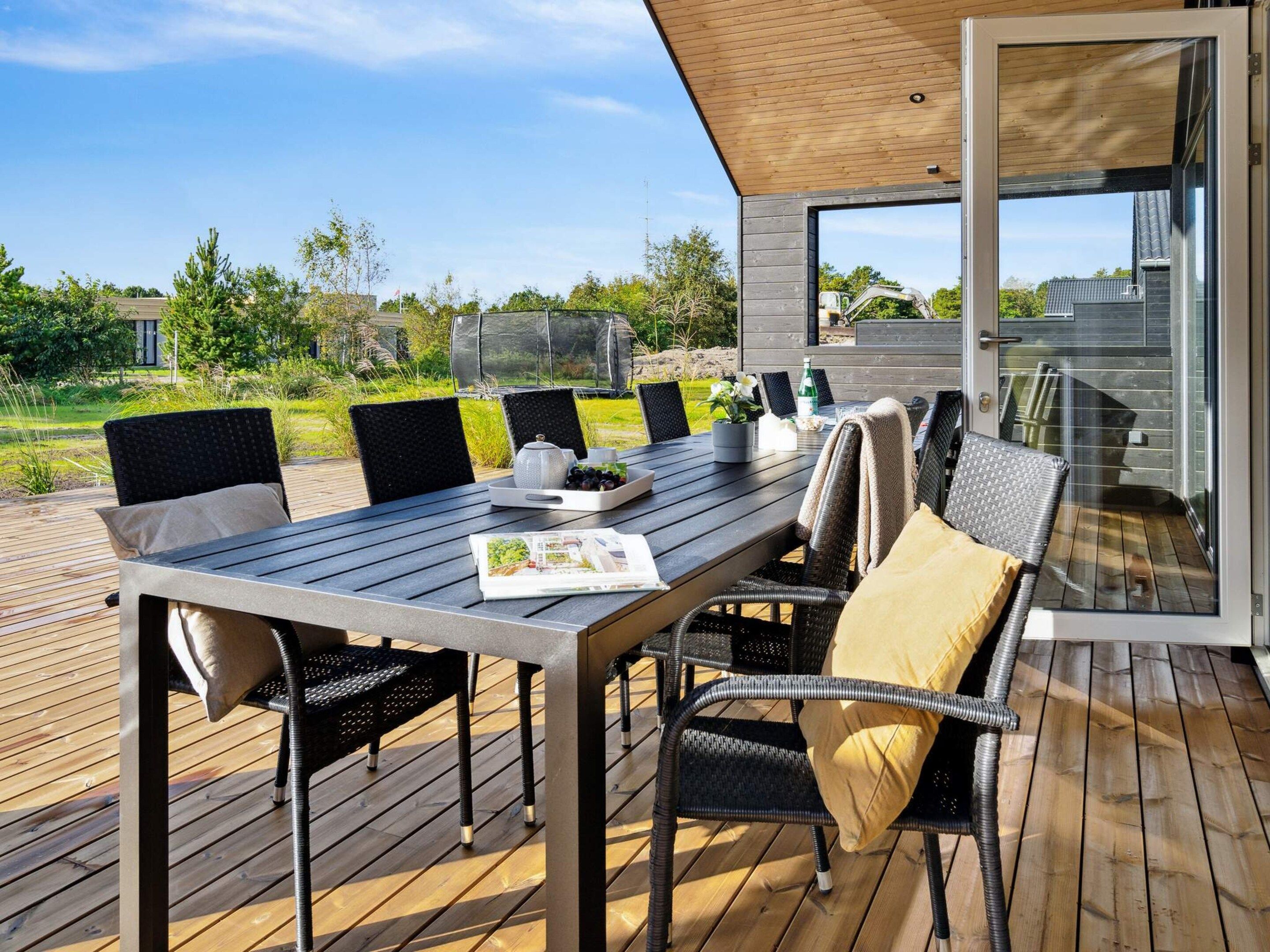 An outdoor dining area with a table, chairs, and a view of the surrounding landscape.