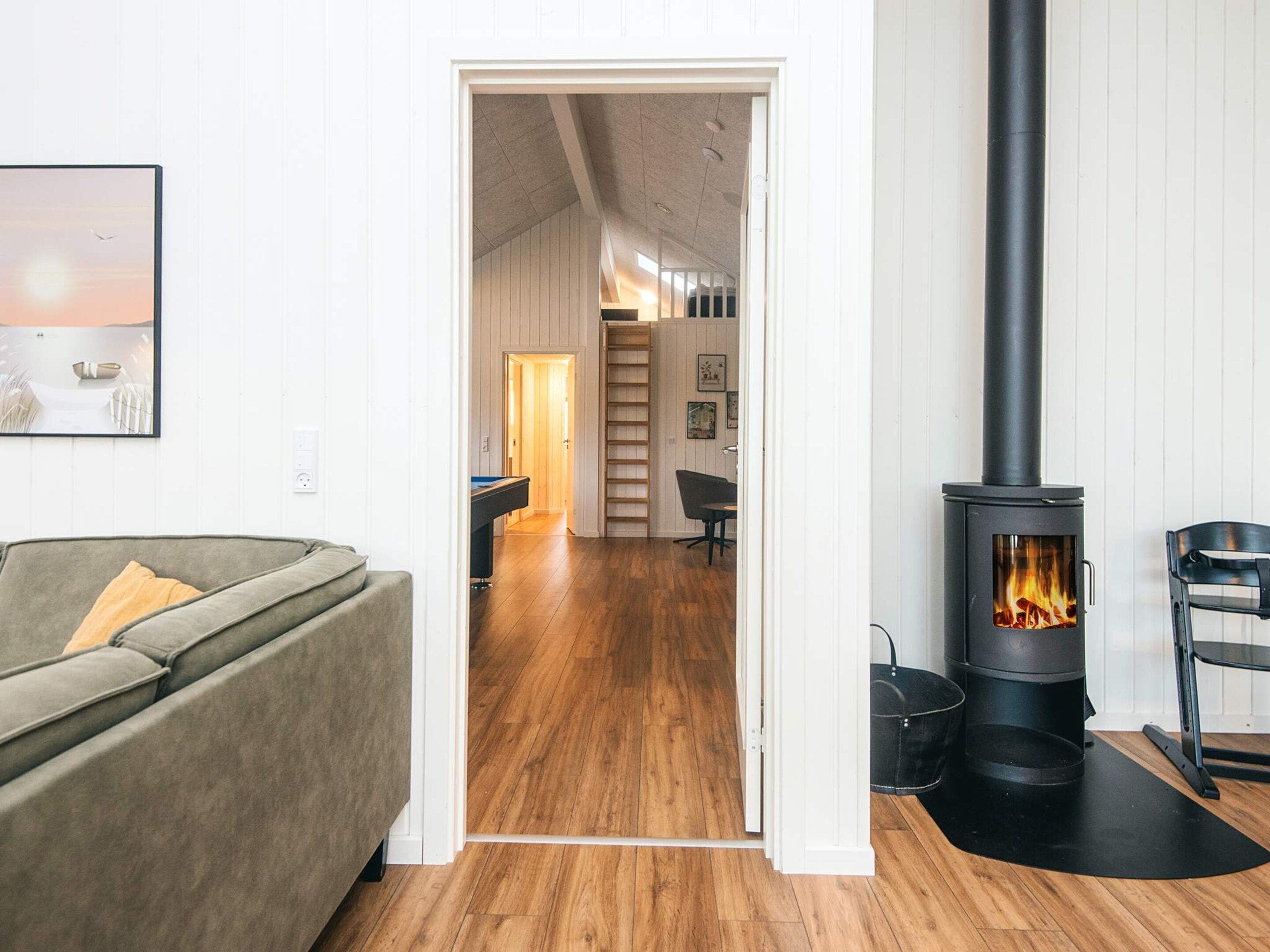 A living room with a sofa, a fireplace, and a hallway leading to a dining area.
