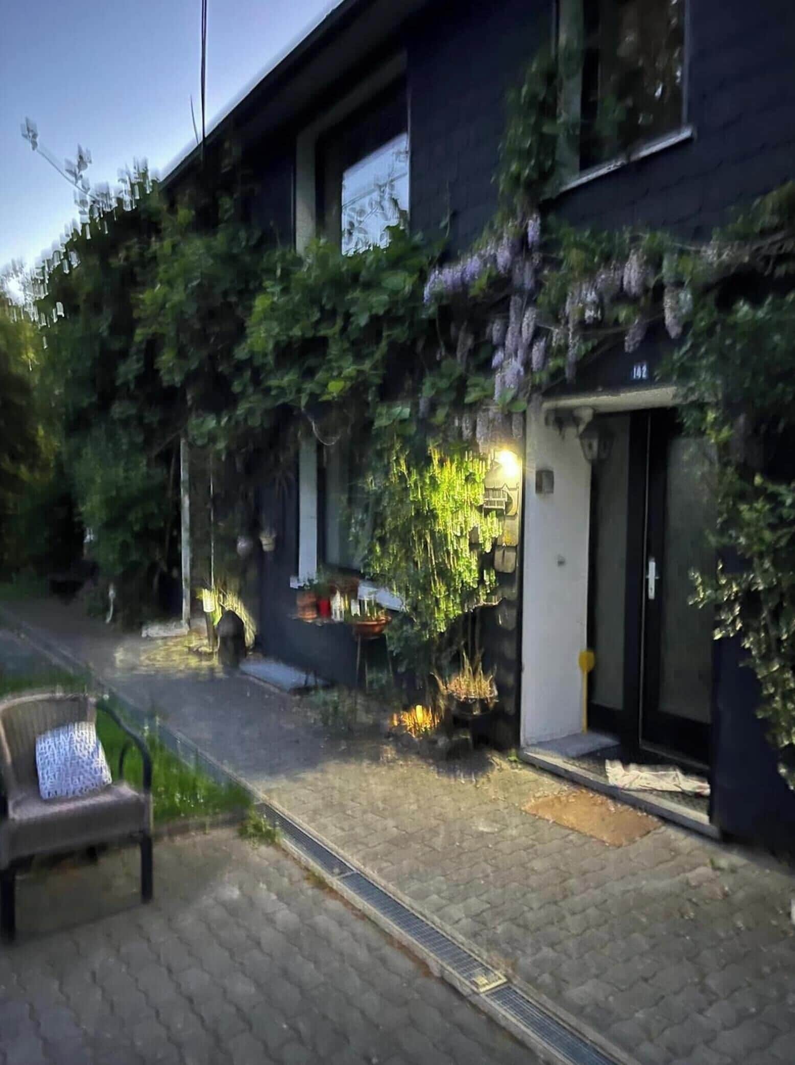 A building with a dark facade, a visible door, and a small outdoor seating area with a bench.