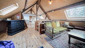 Une pièce de style « loft », avec des poutres apparentes, un lit, un bureau et une grande fenêtre.
