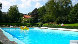 A rectangular swimming pool with clear blue water, surrounded by a paved walkway and lush greenery. - Holiday Home Country House Kathy (Michelstadt)