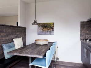 Ein moderner Essbereich mit einem Holztisch, blauen Stühlen und einer hängenden Leuchte.