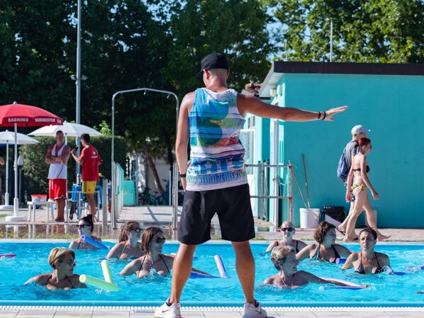Zona de piscina con gente nadando y un socorrista.