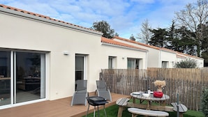 Une maison moderne dotée d’un patio, d’une porte-fenêtre coulissante et d’une terrasse en bois.