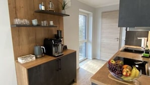 A modern kitchen with wooden cabinetry, a coffee machine, and a fruit bowl. - Near the North Sea Modern Retreat (Esens)
