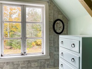 A room with a window overlooking a forest, a dresser with drawers, and a framed picture on the wall. - 10 Person Holiday Home in Kyrkhult (Kyrkhult)