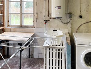 A laundry area with a washing machine, a drying rack, and a window with a view of trees. - 10 Person Holiday Home in Kyrkhult (Kyrkhult)