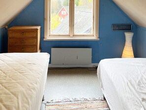 A bedroom with two beds, a dresser, a radiator, a window with a view of a house, and a wall-mounted sign. - 10 Person Holiday Home in Kyrkhult (Kyrkhult)