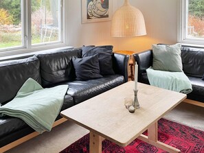 A modern living room with a black leather sofa, a light-colored coffee table, and a red patterned rug. - 10 Person Holiday Home in Kyrkhult (Kyrkhult)