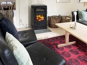 A living room with a black wood-burning stove, a sofa, a table, and a patterned rug.